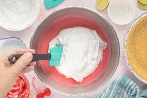 Folding whipped topping into the pink cherry limeade filling with a silicone spatula until light and fluffy.