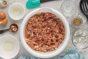 Meatball mixture fully combined in a large white bowl before shaping and baking.