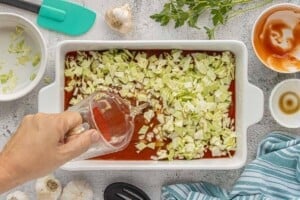 Tomato sauce, chopped cabbage, and water added to a baking dish.
