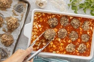 Baked porcupine meatballs placed into tomato sauce and cabbage mixture before finishing in the oven.