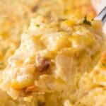 Cheesy hashbrown casserole made with Simply Potatoes topped with melted cheese and served on a spoon above a creamy baked potato casserole dish.