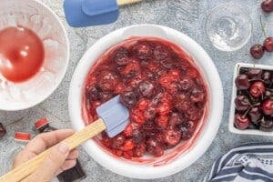 Stirring together thawed frozen cherries, cherry pie filling, vanilla, almond extract, and cornstarch for the cherry crisp filling.