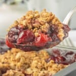 Spoonful of warm cherry crisp with juicy cherries and a buttery oat crumble.