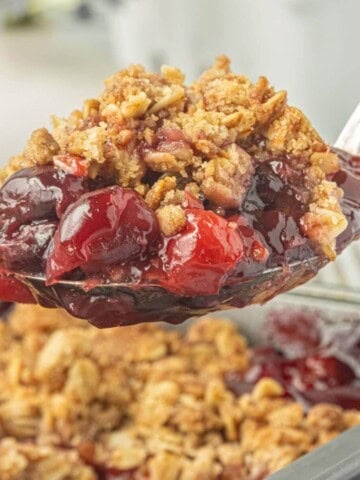 Spoonful of warm cherry crisp with juicy cherries and a buttery oat crumble.