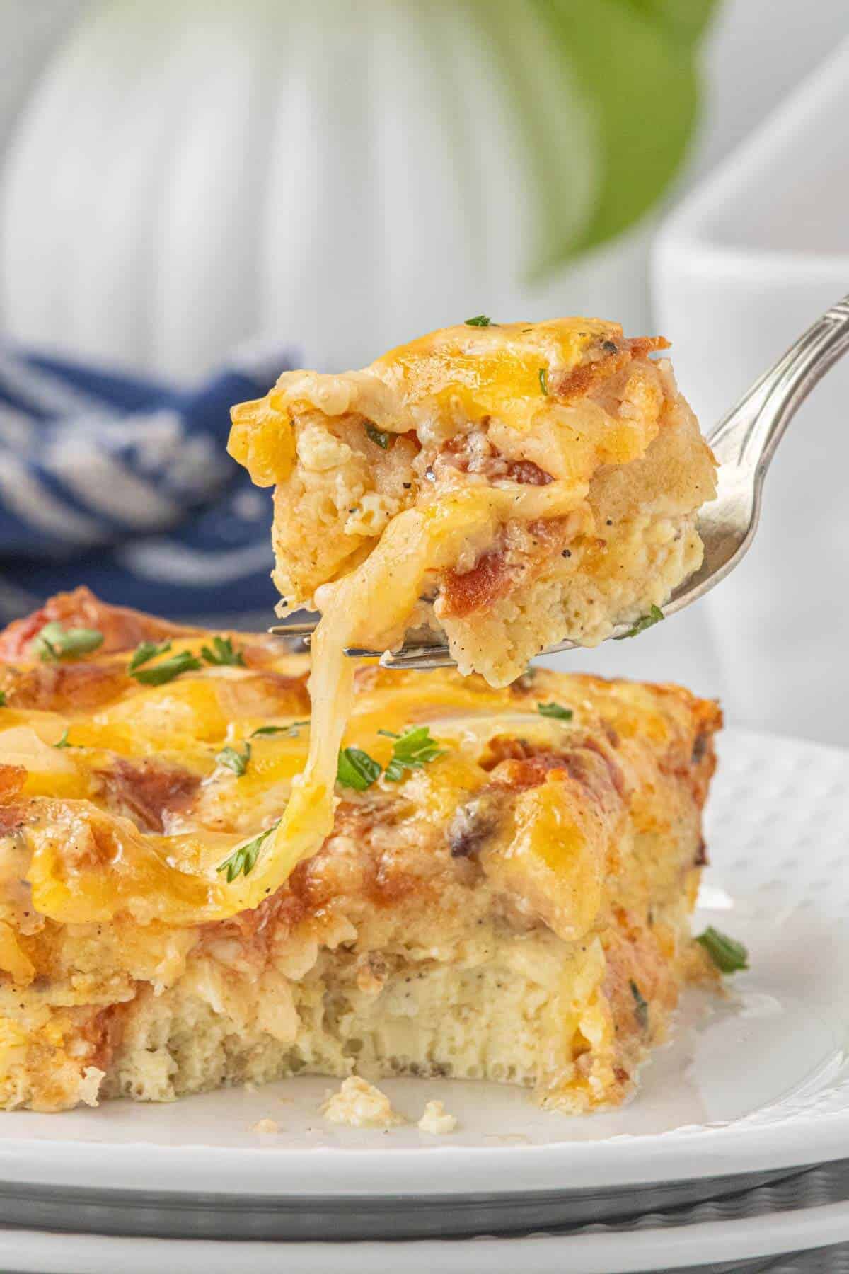 Fork holding a bite of Leftover Pizza Breakfast Casserole with melted cheese and pepperoni.