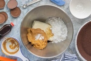 Cream cheese, peanut butter, powdered sugar, vanilla, and salt in a mixing bowl for making no-bake peanut butter cup cheesecake filling.