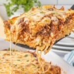 Cheesy slice of spaghetti pie casserole served from a baking dish with layers of spaghetti, seasoned beef sauce, and melted mozzarella cheese.