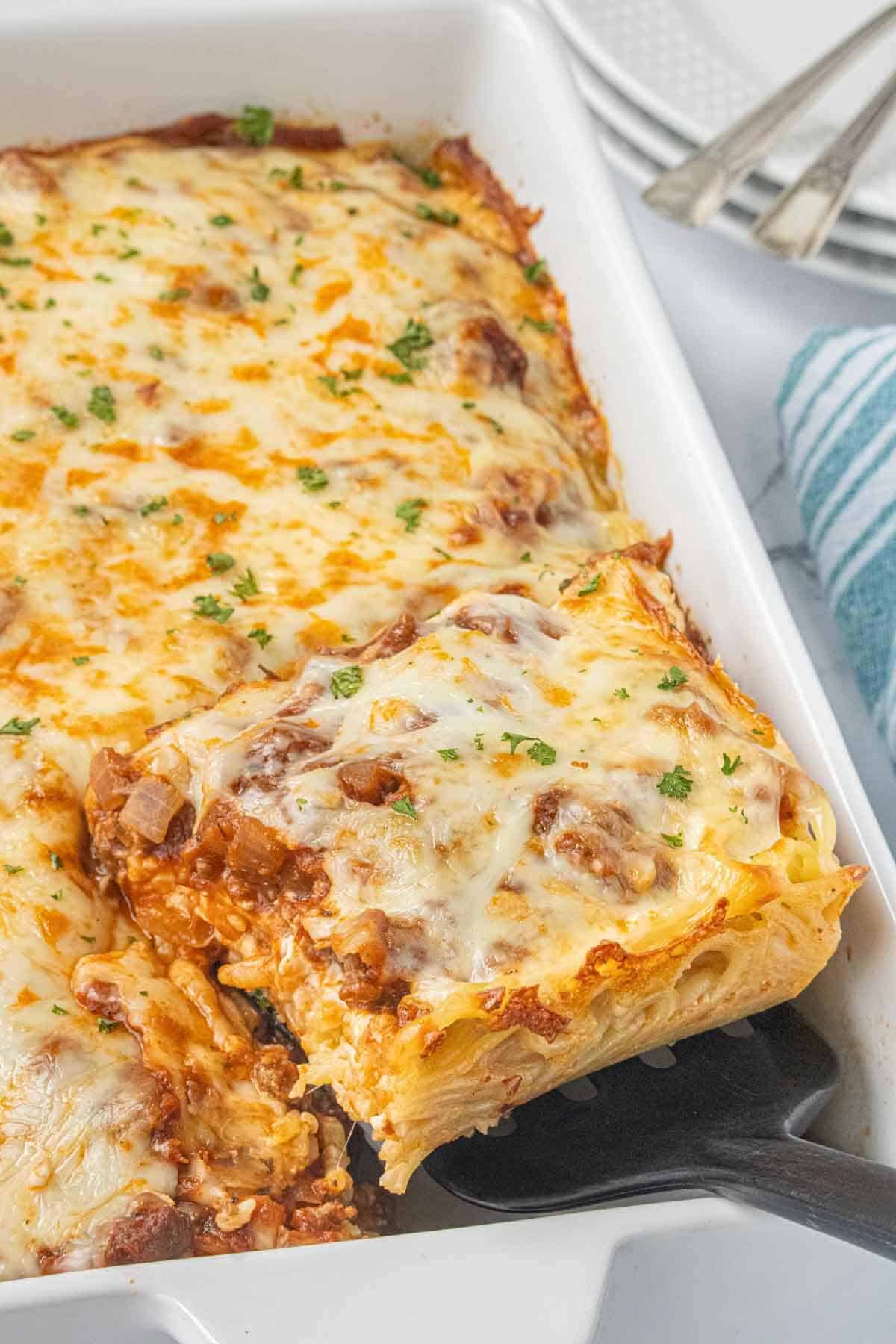 A casserole dish of spaghetti pie with a spatula lifting out a generous slice.