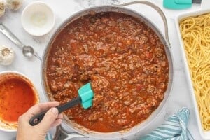 Meat sauce simmering in a skillet with ground beef, tomato sauce, and seasonings.