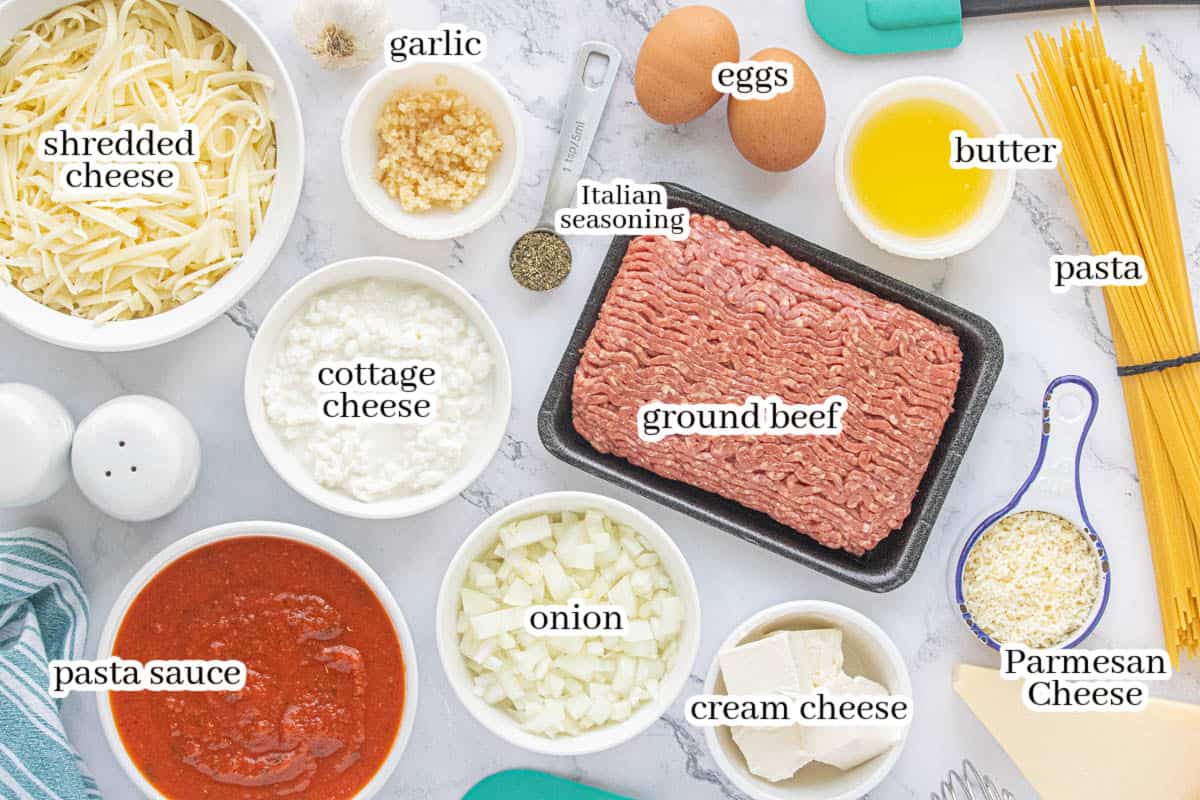 Ingredients for the spaghetti pie casserole laid out on a white counter top. With print overlay for clarification.