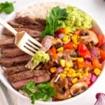 Steak bowl recipe with sliced steak, rice, saut&eacute;ed mushrooms, sweet corn, bell peppers, red onion, and creamy avocado.
