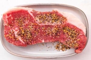 Ribeye steak seasoned with Montreal steak seasoning on a plate.