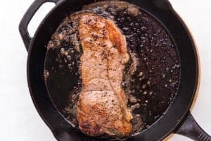 Steak cooking in a cast iron skillet.