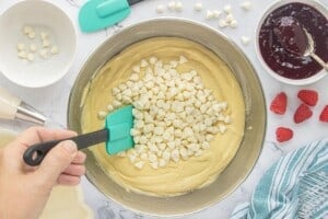 Folding white chocolate chips into cake batter.