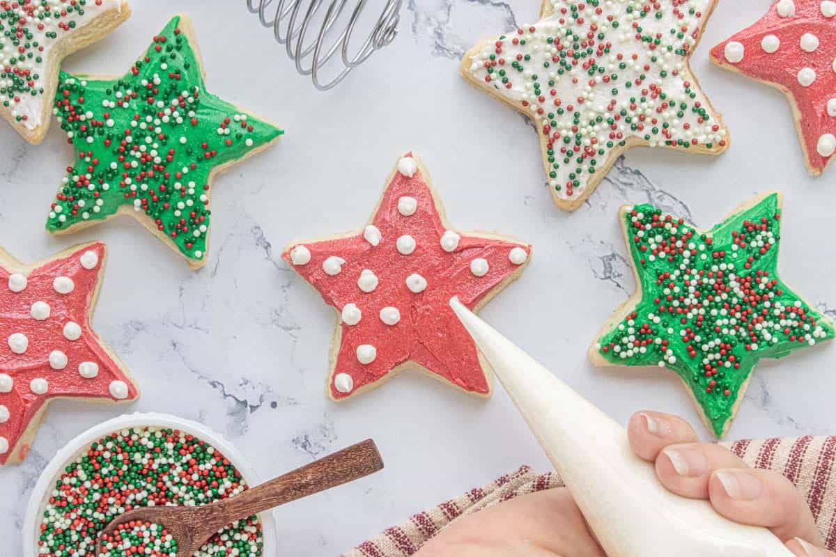 Decorating Christmas star sugar cookies with colorful buttercream frosting and sprinkles.