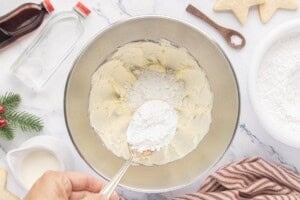 Adding powdered sugar to softened butter to make buttercream sugar cookie frosting.