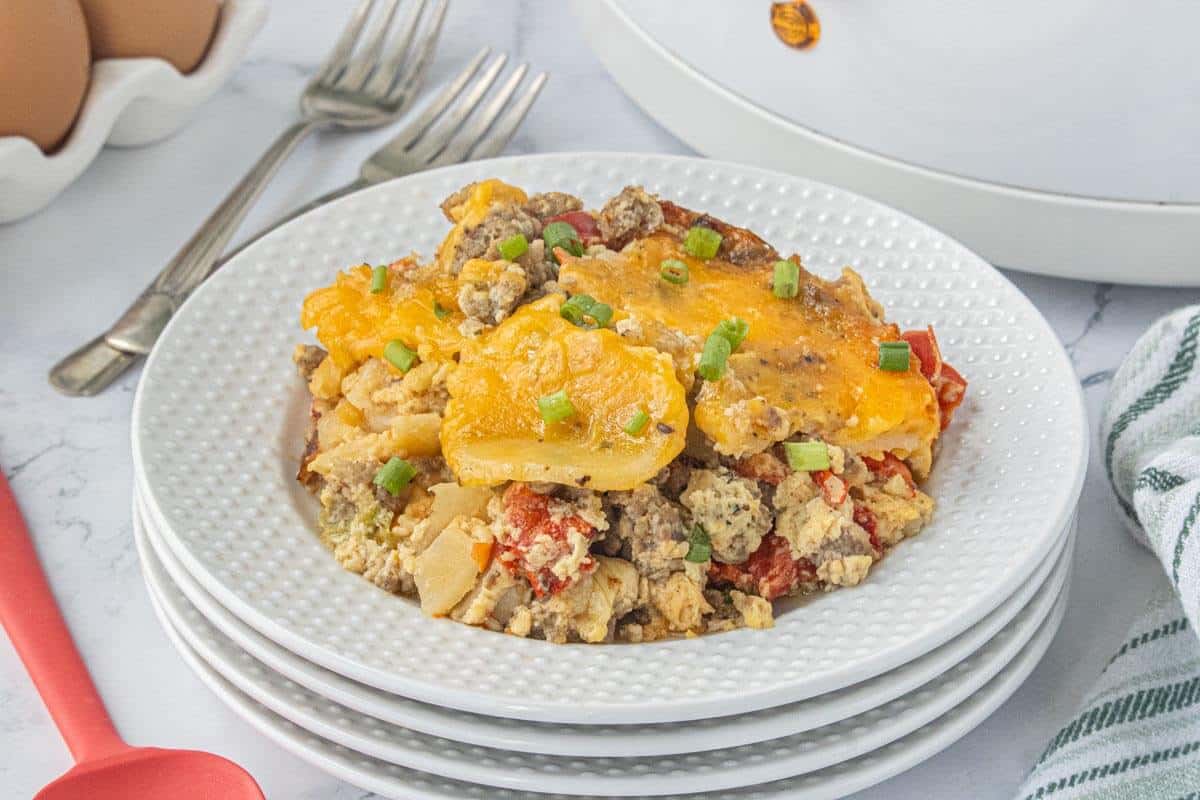 Plated serving of breakfast casserole topped with green onions and melted cheddar cheese.