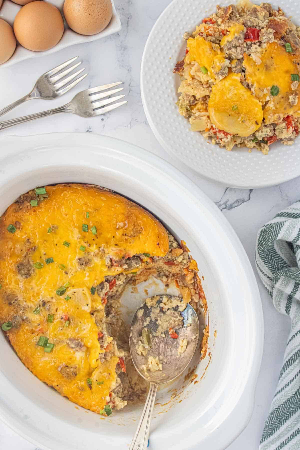 Slow cooker Christmas breakfast casserole topped with melted cheddar cheese, served on a white plate.