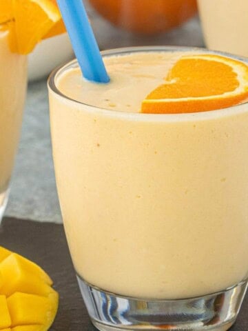 Close-up of a thick and creamy Mango Orange Creamsicle Smoothie garnished with a fresh orange slice.