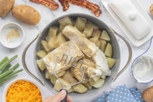 Tender boiled potatoes in a large pot butter, cream cheese, sour cream, and seasonings before mashing.
