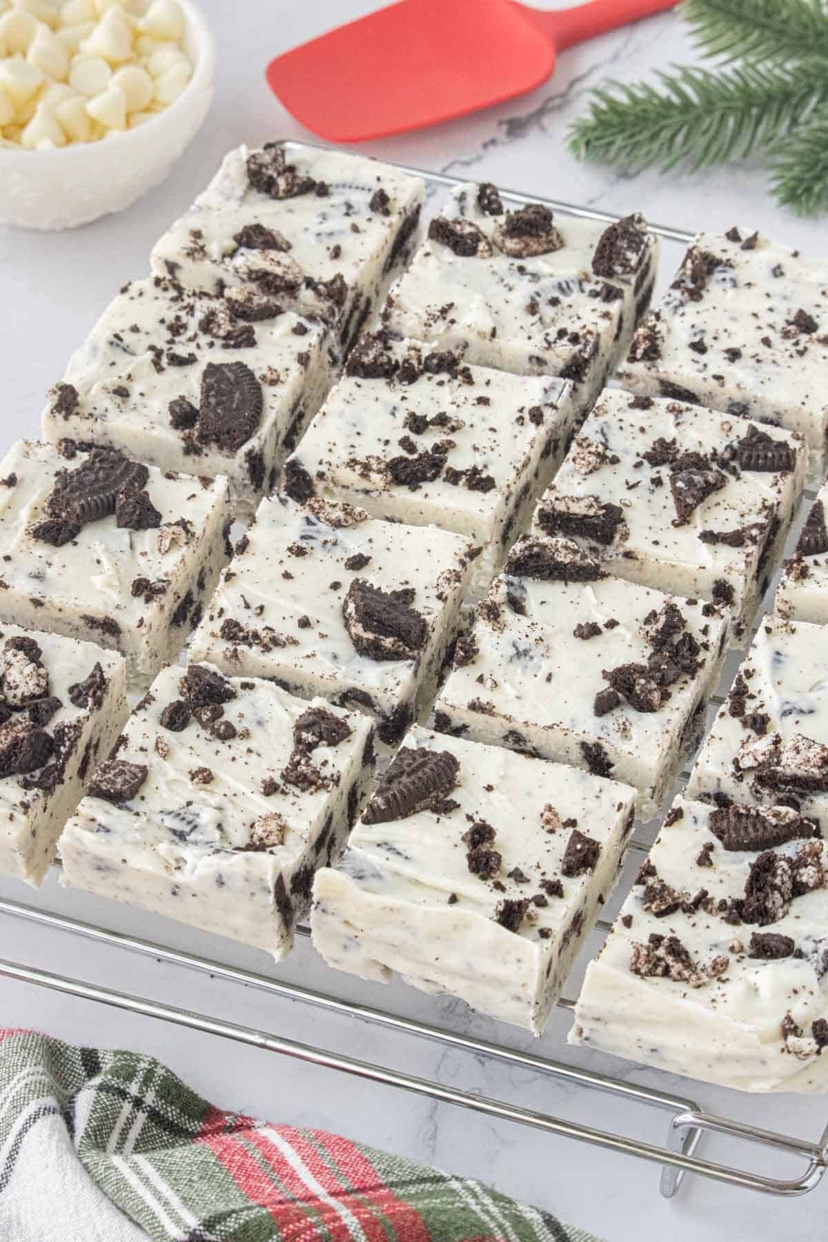 A batch of easy Oreo fudge cut into squares and topped with chopped Oreo cookies on a cooling rack.