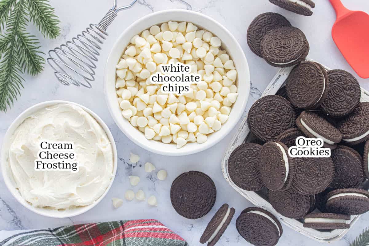 Three ingredients for Oreo fudge including cream cheese frosting, white chocolate chips, and Oreo cookies arranged on a countertop before making the recipe.