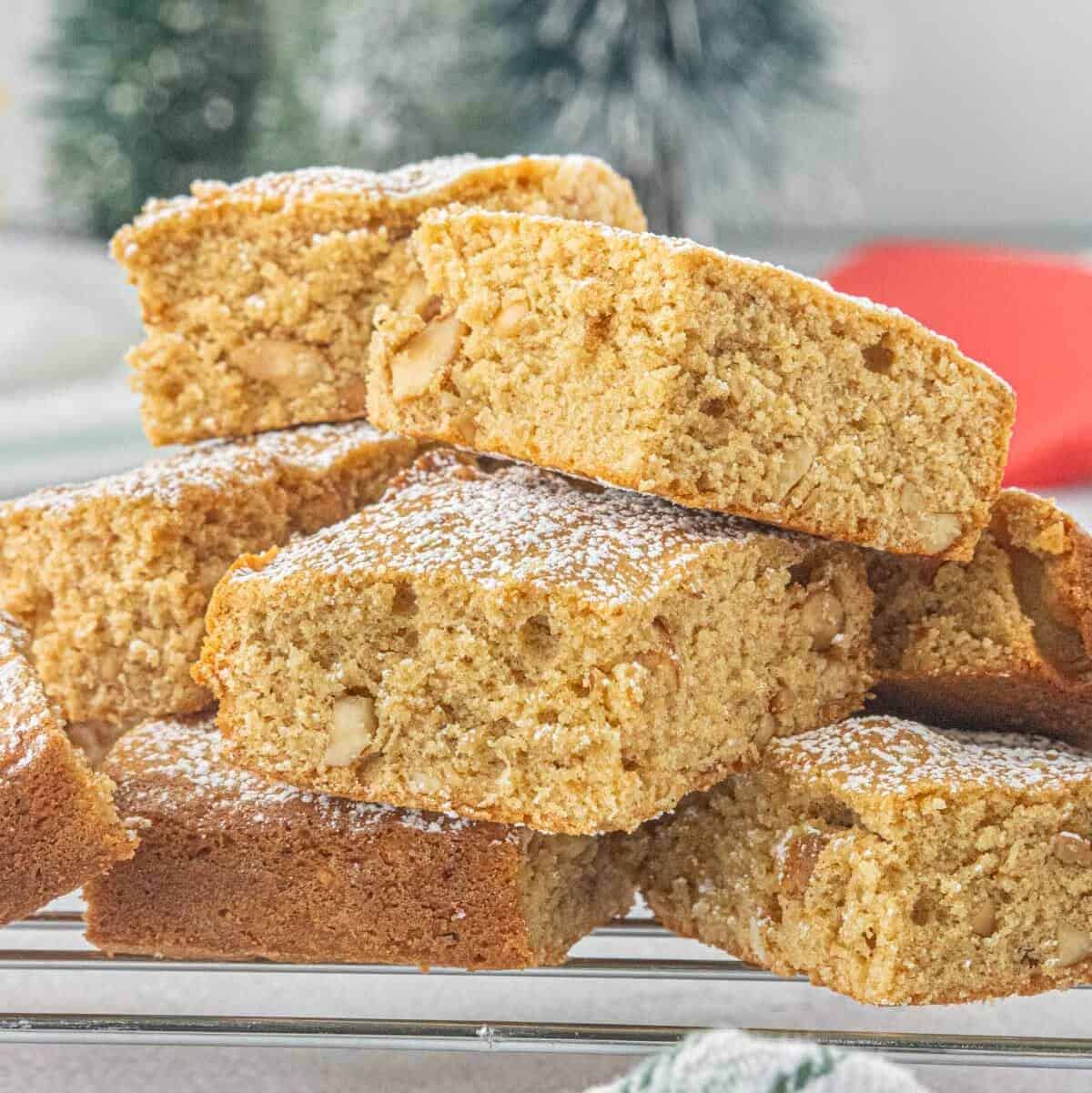 Stacked peanut butter blondies dusted with powdered sugar on a cooling rack, showing their soft, chewy texture and chopped peanuts throughout.