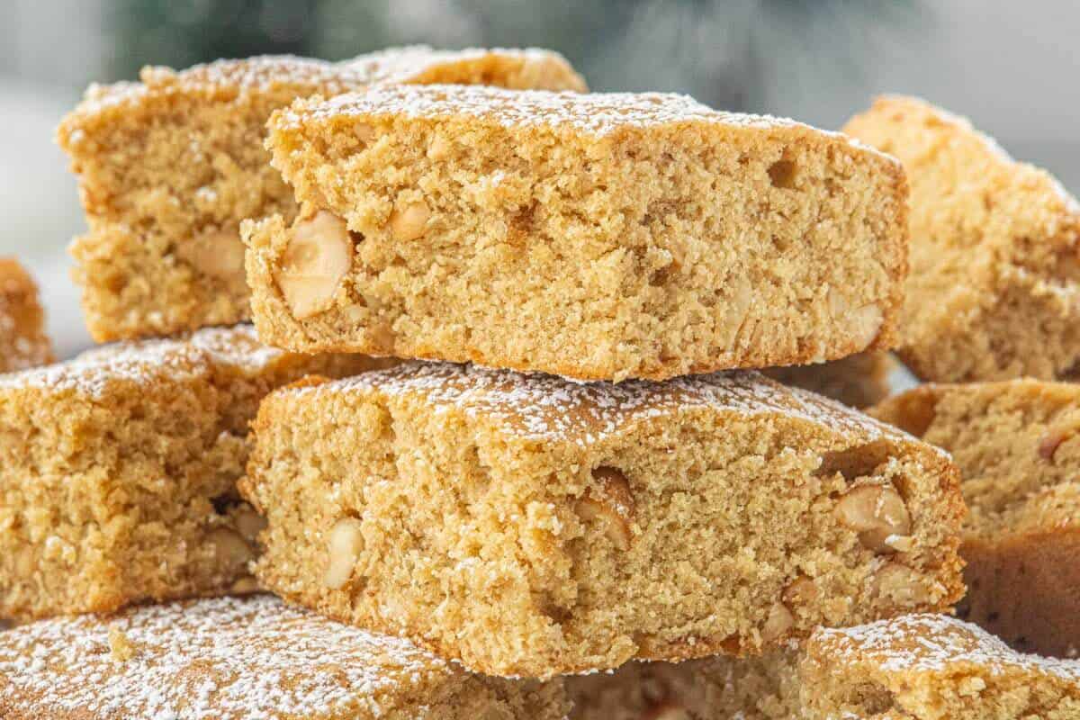 Close-up of chewy peanut butter blondies topped with powdered sugar and stacked to highlight the tender crumb and crunchy peanut pieces.
