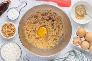 An egg is being added to the creamed peanut butter mixture in a large mixing bowl while preparing blondie batter.