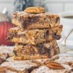 Stack of Graham Cracker Pecan Cookie Bars on a cake server, showing the chewy center packed with chocolate chips, pecans, and coconut.
