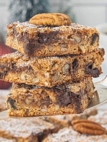 Stack of Graham Cracker Pecan Cookie Bars on a cake server, showing the chewy center packed with chocolate chips, pecans, and coconut.