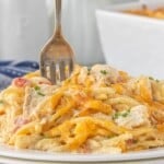 Fork stuffed into a white plate piled high with chicken spaghetti.