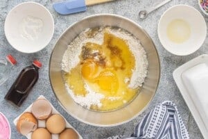 White cake mix, melted butter, egg, egg yolk, vanilla, pudding mix, and almond extract combined in a mixing bowl before stirring.