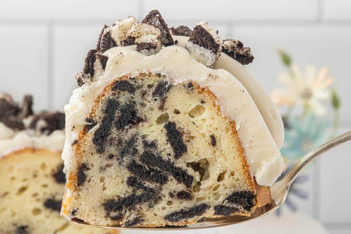 Close-up of a sliced Oreo Bundt Cake topped with creamy frosting and chopped Oreo cookies.