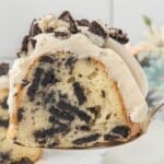 Slice of Oreo Bundt Cake on a cake server showing Oreo cookie pieces baked throughout the cake.