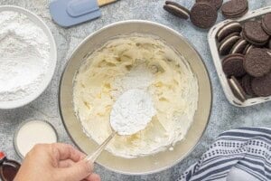 Powdered sugar being added to the creamy frosting mixture.
