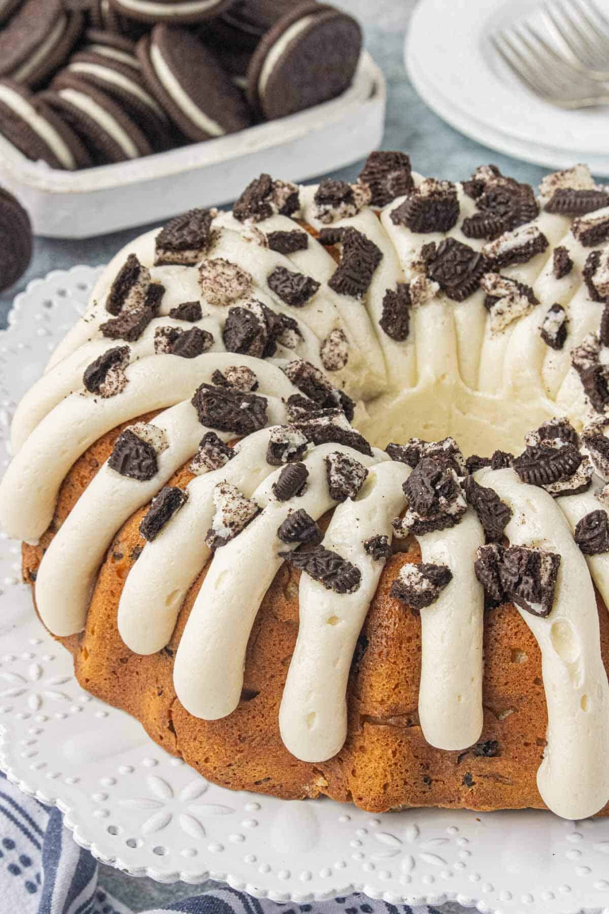Oreo Bundt Cake topped with thick ribbons of creamy frosting and chopped Oreo cookies.