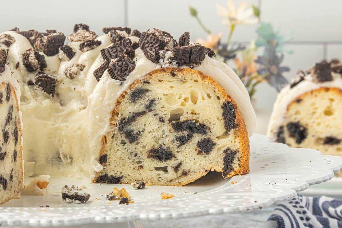 Cut Oreo Bundt Cake on a serving platter showing cookies baked throughout the tender cake.