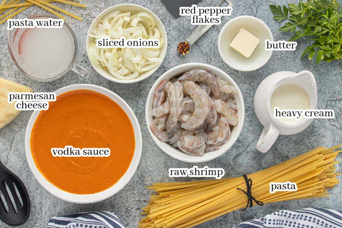 All of the ingredients to make the pink shrimp pasta on a countertop. With print overlay for clarification.