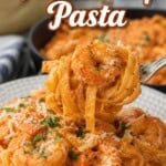 Pinterest pin of Pink Shrimp Pasta with creamy vodka sauce, tender shrimp, Parmesan, and parsley, with a forkful of pasta lifted above the plate.