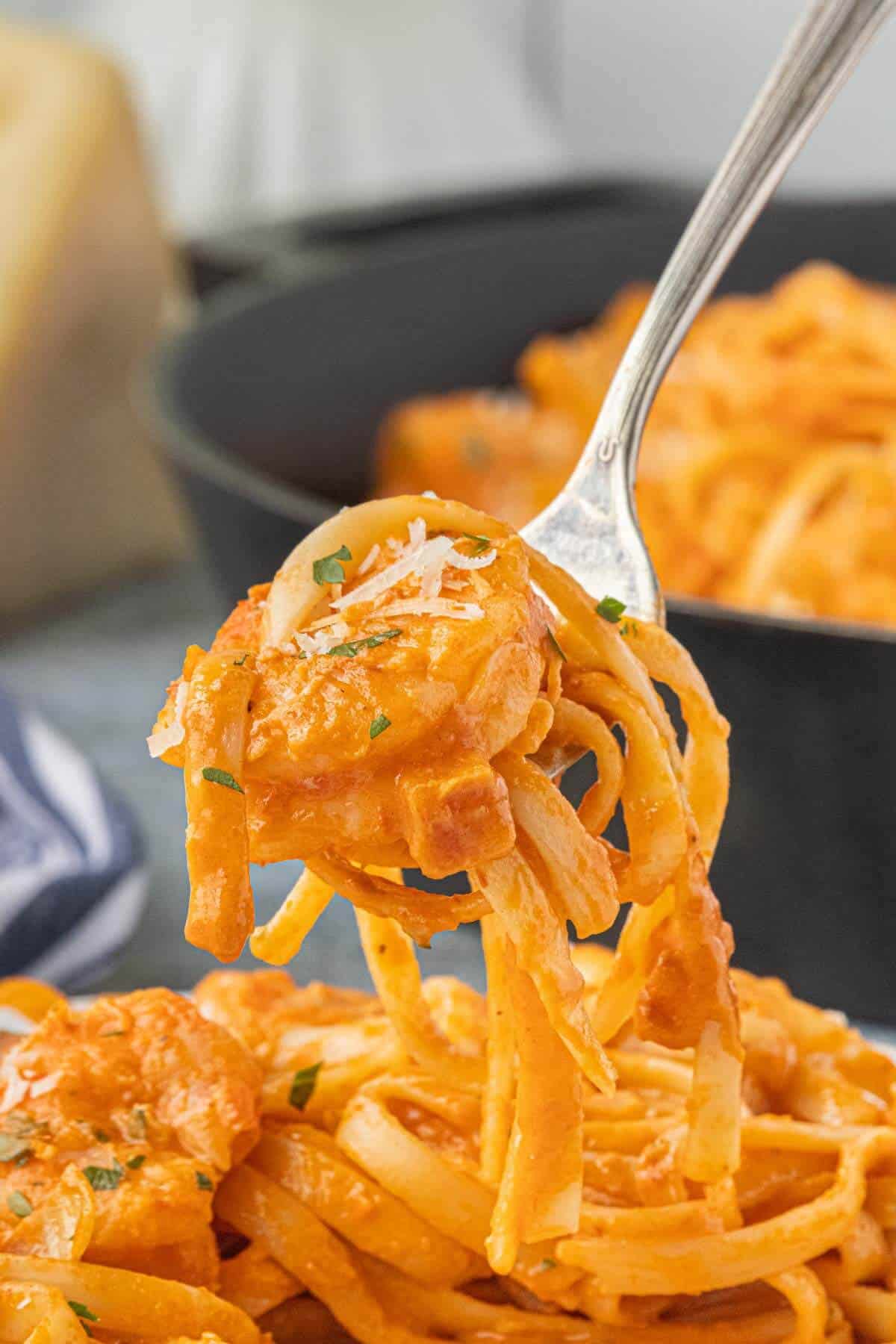 Forkful of tender pink shrimp pasta coated in creamy tomato vodka sauce with Parmesan and parsley.