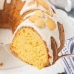 A close-up of a slice of Vanilla Wafer Bundt Cake with vanilla glaze and crushed vanilla wafers is served on a cake server, showing the moist, tender crumb.