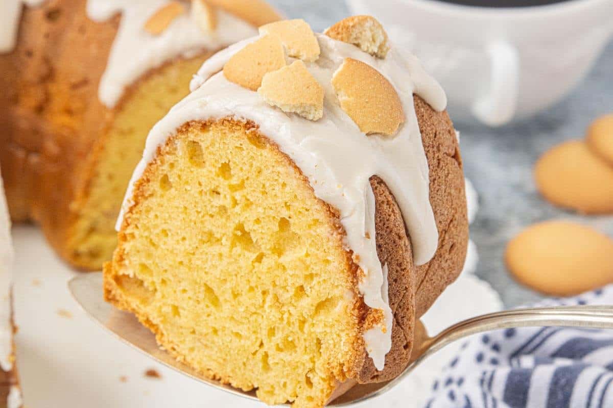 Close-up of a moist slice of Vanilla Wafer Bundt Cake with vanilla glaze and crushed vanilla wafer cookies served on a cake server.