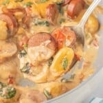 Spoonful of creamy potato gnocchi with browned chicken sausage, spinach and sun-dried tomatoes.