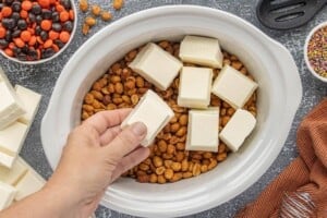Honey roasted peanuts topped with chunks of vanilla almond bark in a slow cooker.