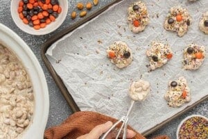 Scooping the melted peanut candy mixture onto a parchment-lined baking sheet.