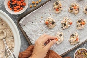 Adding orange and black M&M's to freshly scooped candies topped with Halloween sprinkles.
