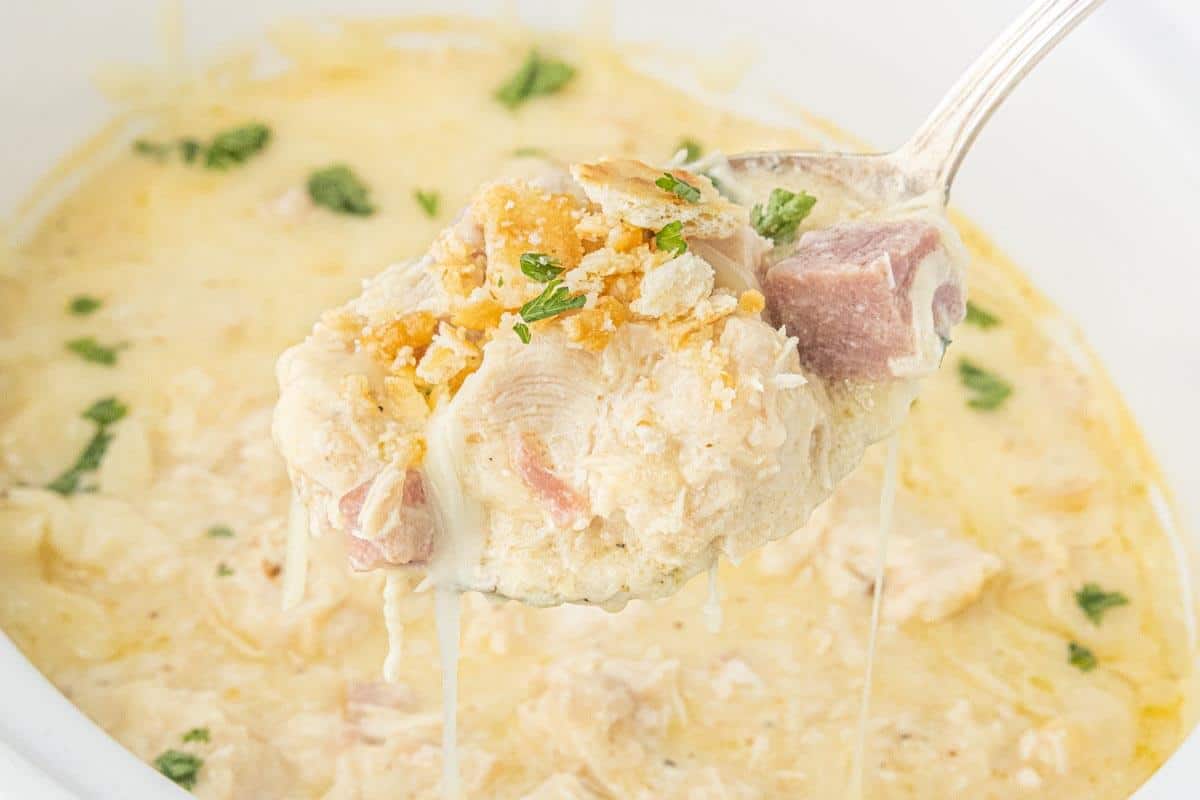 Spoonful of creamy chicken and ham with melted Swiss cheese and buttery cracker topping lifted from the crockpot.