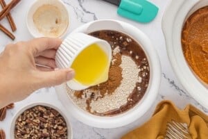 Pouring melted butter over cake mix and spices in a mixing bowl.