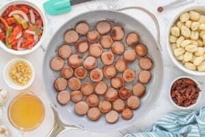 Sliced chicken sausage browning in a large skillet.